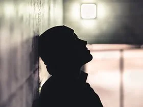 silhoutte of a man with his head resting against the wall
